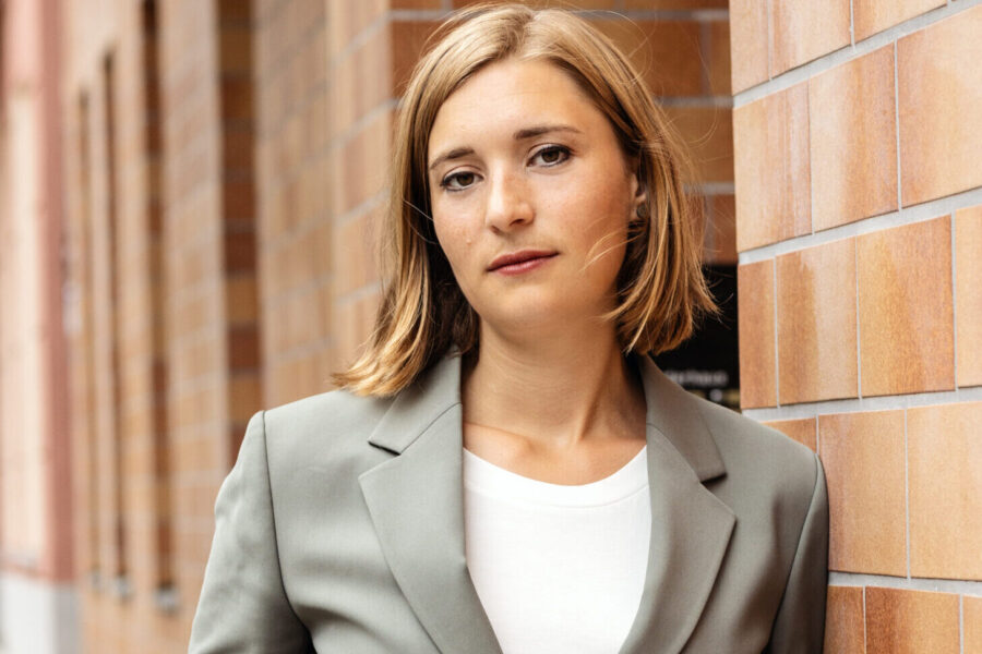 Hanna Steinmüller lehnt an einer Hauswand.